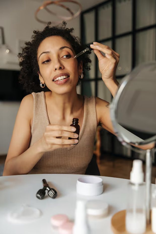 A woman applying a skincare product at her dressing table